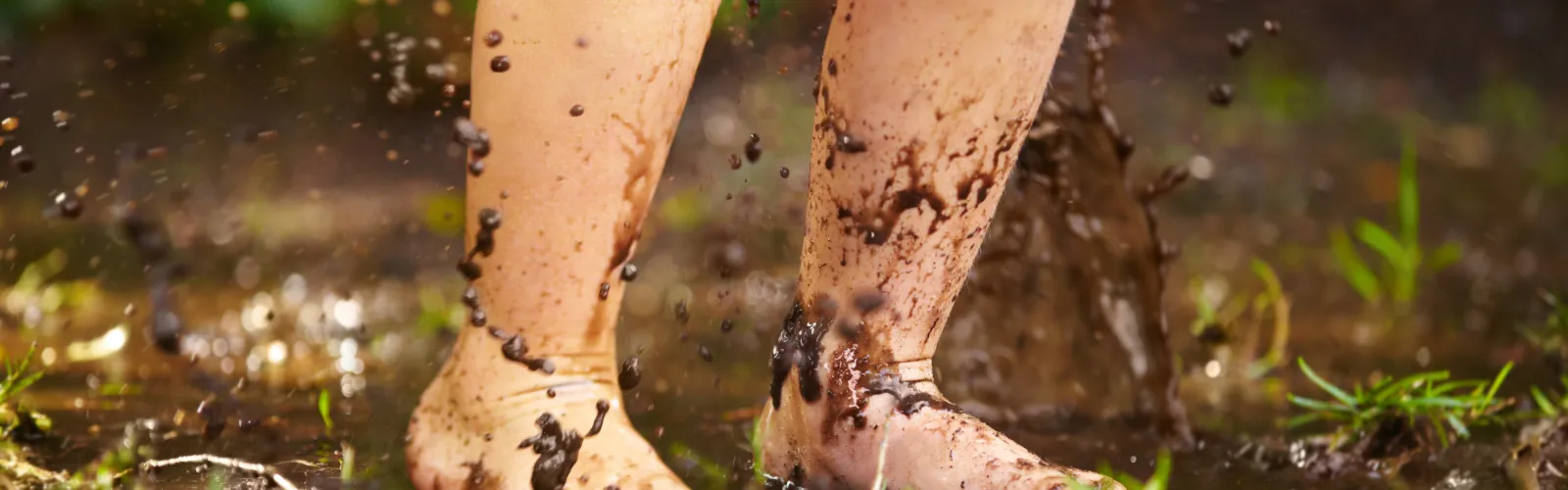 Child jumping in puddle and mud after the rain